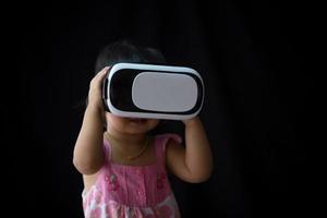 Kind mit Virtual-Reality-Brille im modernen Coworking-Studio. Laptop mit VR-Headset auf schwarzem Hintergrund foto