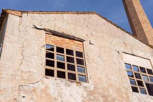 Colseup von unten von ein Fenster von ein alt verlassen grau Papier Mühle mit ein Backstein Kamin Rohr foto