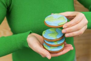 Erde Tag Konzept. Stapel von Kekse im das gestalten von das Erde im weiblich Hände. foto
