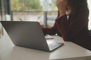 Schuss von ein asiatisch jung Geschäft weiblich Arbeiten auf Laptop im ihr Arbeitsplatz. foto