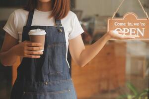 Startup erfolgreicher Kleinunternehmer SME Schönheitsmädchen steht mit Tablet-Smartphone im Café-Restaurant. Porträt der Barista-Café-Besitzerin mit asiatischer Bräune. KMU-Unternehmer-Verkäufer-Geschäftskonzept foto