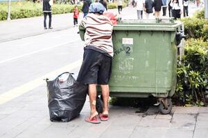 Frau sammelt Müll, Karton und Plastik zu nehmen es zum wird bearbeitet und erhalten Geld zum Lebensmittel. Jakarta, Indonesien, kann 1, 2024 foto