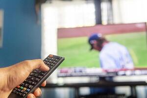 Hände halten ein Fernbedienung Steuerung Ändern Kanäle. Fernseher Industrie Konzept. foto