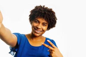 pov von schwarz lockig jung Frau tragen Hosenträger nehmen ein Selfie Über Weiß Hintergrund. foto