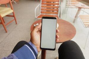 Hand des jungen Mannes mit Smartphone mit grünem Bildschirm im Café foto