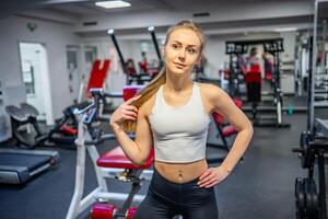 jung sportlich Frau tragen Sportbekleidung posieren Vor tun Übung mit Fitness Ausrüstung beim Fitnessstudio, sie Übung zum stark und gut . hoch Qualität Foto