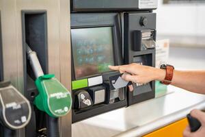 schließen oben Aussicht von Mann Hand zahlt sich aus zum Treibstoff mit ein Anerkennung Karte auf Terminal von Selbstbedienung Füllung Bahnhof im Europa foto