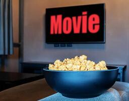 Popcorn im schwarz Schüssel mit Fernsehen rot Text Film auf Anzeige Fernsehen im Leben Zimmer foto