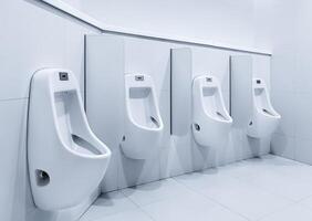 Herrentoilette mit weißen Porzellan-Urinalen in Reihe foto