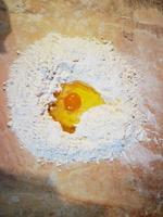 Mehlbrunnen mit Ei im Inneren, um einen Teig für Kuchen in der italienischen Küche zu machen foto