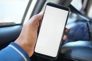 Hand, die ein Smartphone mit leerem Bildschirm in einem Auto hält foto