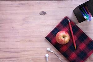 Schwarz zum Schulkonzept mit Apfel auf Notizblock auf dem Tisch. foto