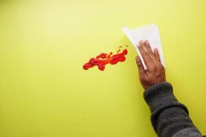 Hand im Blau Gummi Handschuhe Reinigung Tomate verschütten mit ein Gewebe foto