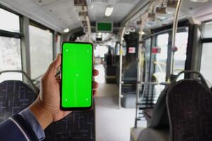 Passagier Sitzung im ein Bus mit seine Telefon mit Grün Bildschirm foto