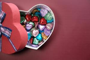 oben Aussicht von Süßigkeiten im ein Herz gestalten Geschenk Box auf rot Hintergrund foto