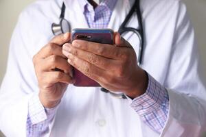 glücklich Arzt Mann SMS auf ein Clever Telefon isoliert auf ein Weiß Hintergrund foto