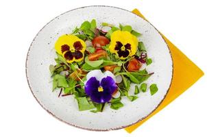 Gemüsesalat mit essbaren Blumen auf weißem Hintergrund. foto