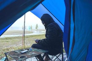 asiatische Mannreisen entspannen sich im Urlaub. Camping am Berg. sitzen Sie entspannt auf dem Stuhl. in der atmosphäre regen fallen haben nebel nach unten. Thailand foto