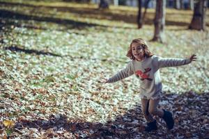 kleines Mädchen, das im Herbst in einem Stadtpark spielt foto