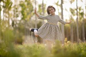 kleines Mädchen im Naturfeld, das ein schönes Kleid trägt foto