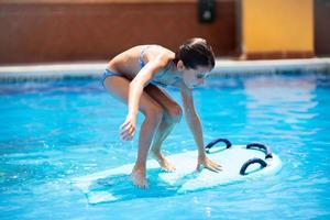 süßes Mädchen spielt mit einem Bodyboard in einem Schwimmbad. foto