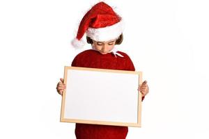 kleines Mädchen mit Weihnachtsmütze mit leerem Brett foto