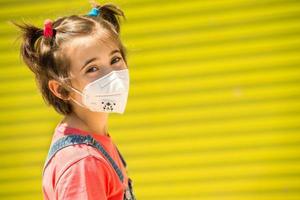 Kindermädchen, das während der Covid-19-Pandemie eine Schutzmaske gegen Coronavirus trägt foto