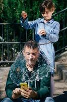 Mädchen bläst einen mit Wasser gefüllten Ballon über dem Kopf ihres Vaters auf foto