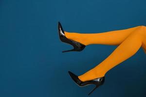 Beine der schönen Frau in stilvollen Schuhen auf farbigem Hintergrund foto
