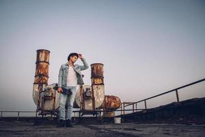 Mann mit Skateboard auf einem Hintergrund von rostigen Rohren foto