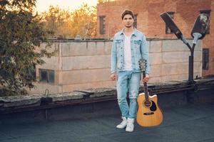 junger Mann mit Gitarre in der Stadt auf Sonnenstrahlen Hintergrund foto