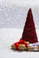 Weihnachtsbaum mit Geschenken auf dem Schnee vor dem Hintergrund heller Bokeh-Lichter. minimales Konzept der Postkarte, Einladungskarte. Nahaufnahme mit Textfreiraum foto