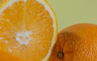 halbierte Orange in der Nähe einer ganzen Orange auf grünem Hintergrund foto