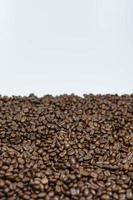 Kaffeebohnen verstreut auf einem vertikalen Foto mit weißem Hintergrund