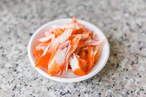 Krabbenstäbchen in Scheiben geschnitten auf Schüssel für gekochtes Essen Salat