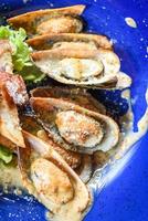 gegrillte Muschelschale Schinken Gemüse und Sauce Meeresfrüchte auf dem Tisch serviert - Schalentiere Meeresfrüchteplatte frische Muscheln mit Käse gebacken Abendessen gekocht