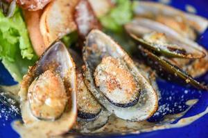 gegrillte Muschelschale Schinken Gemüse und Sauce Meeresfrüchte auf dem Tisch serviert - Schalentiere Meeresfrüchteplatte frische Muscheln mit Käse gebacken Abendessen gekocht