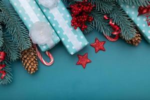 Weihnachten flach Hintergrund mit Geschenken, Beeren und Kiefer auf türkisfarbenem Hintergrund