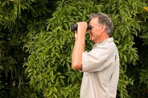 Senior reifer Mann draußen genießen die Natur durch ein Fernglas schauen foto