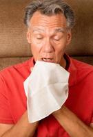 Mann mit Grippe, der in seinem Haus in ein Taschentuch niest foto