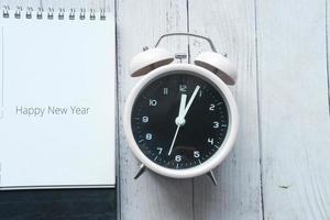 Frohes neues Jahr Text im Kalender mit Uhr auf dem Tisch