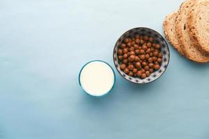 Draufsicht auf Schokoladencornflakes, Milch und Brot auf Blau foto