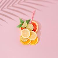 Glas von erfrischend trinken gemacht von Zitrone, Kalk, Orange und Grapefruit Scheiben, Stroh und Grün Blätter mit Palme Baum Blatt Schatten auf Rosa Hintergrund. kreativ Sommer- trinken minimal Konzept. eben legen. foto