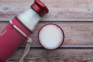 Flasche mit Milch und Glas von Milch auf hölzern Tisch. foto