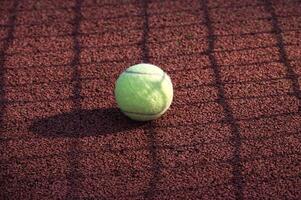 Gelb Tennis Ball ist ruhen auf Tennis schwer Gericht Oberfläche foto