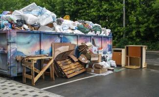 Metall haltbarer blauer industrieller Mülleimer für Müll im Freien auf der Baustelle. großer Abfallkorb für Haus- oder Gewerbemüll. ein Haufen Müll. Ukraine, Kiew - 09. August 2021. foto