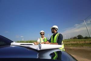 Wind Turbine Ingenieure Arbeiten auf das Dach von Auto beim ein Wind Turbine Feld, Überprüfung und Vergleichen das Entwurf und Bedingung von das Turbine elektrisch Leistung foto