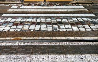 Fußgänger Kreuzung Über das Straßenbahn Spuren auf ein Kopfsteinpflaster Gehweg. foto