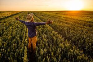 afrikanisch Farmer ist Stehen im seine wachsend Weizen Feld. er ist zufrieden mit Fortschritt von Pflanzen. foto