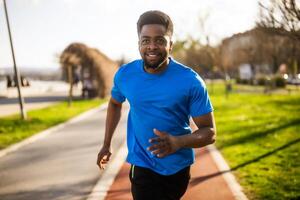 jung Afroamerikaner Mann ist Joggen im das Stadt. foto